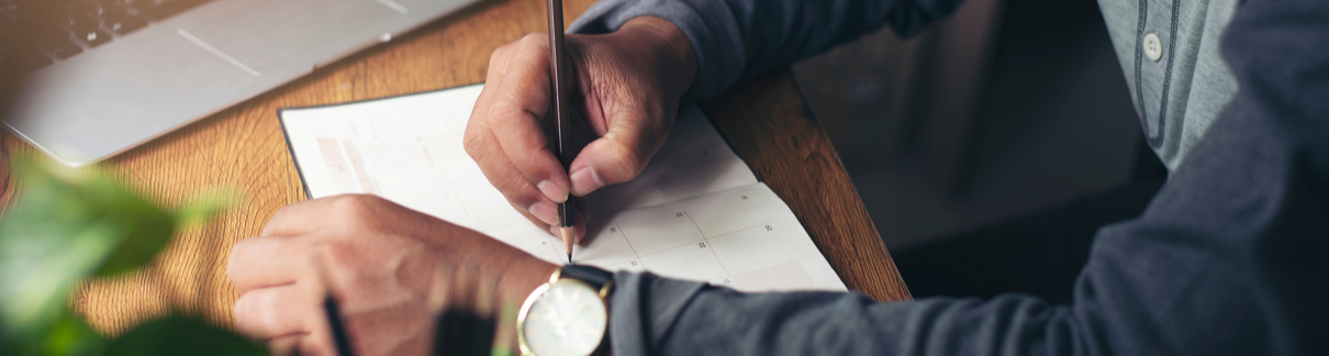 A man writing notes in a planner.