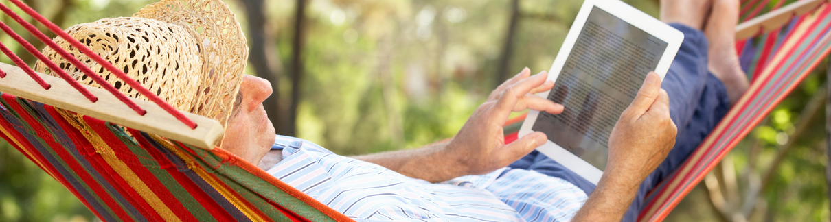 A man in a hammock using a tablet.