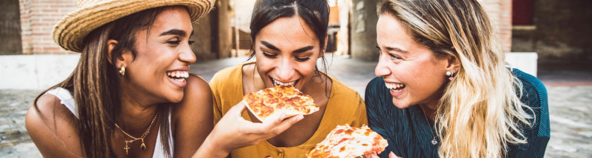 Three women eating pizza in an exotic location