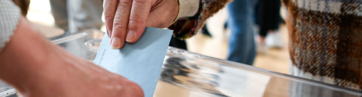 A person putting a ballot paper into a box.