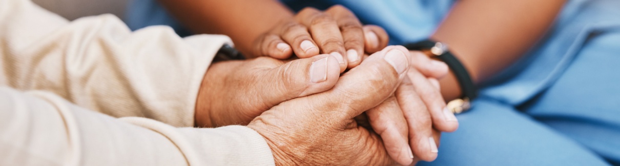 An elderly person holding hands with a nurse.