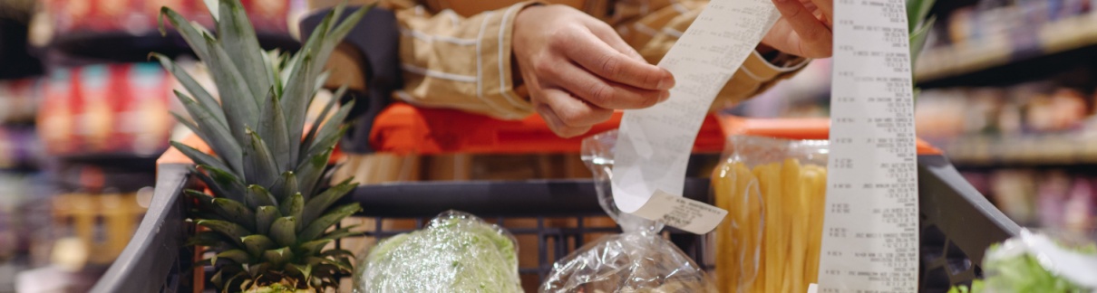 A woman looking at a receipt in a supermarket.