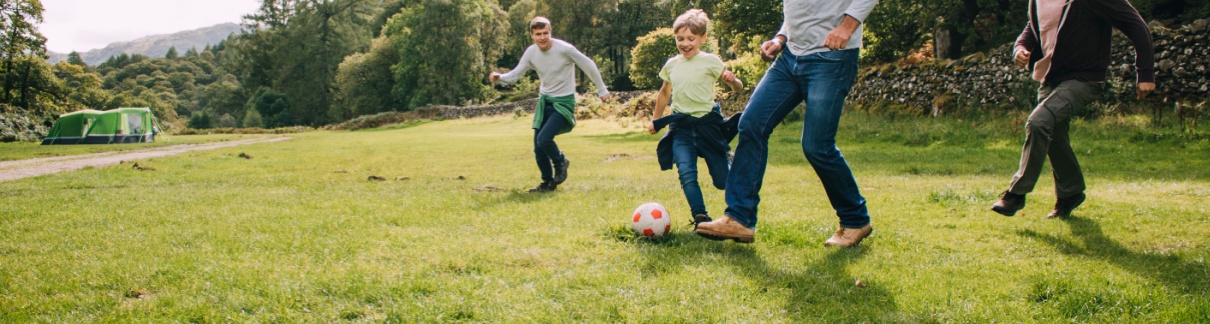 Multi-generational family playing football in a park.