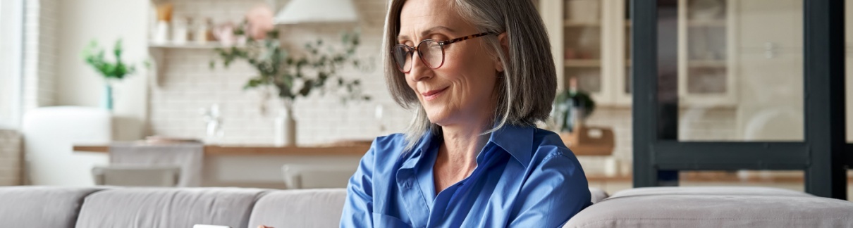 A woman in her 60s checking something on her mobile phone.