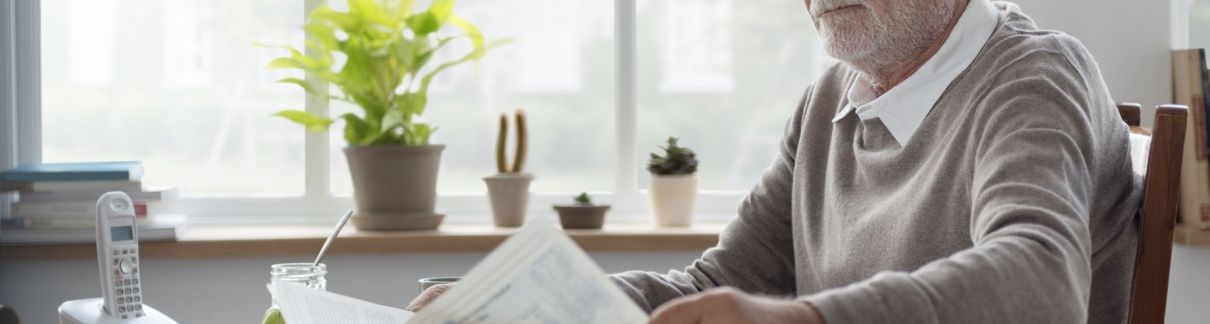 A man reading a newsletter at home.