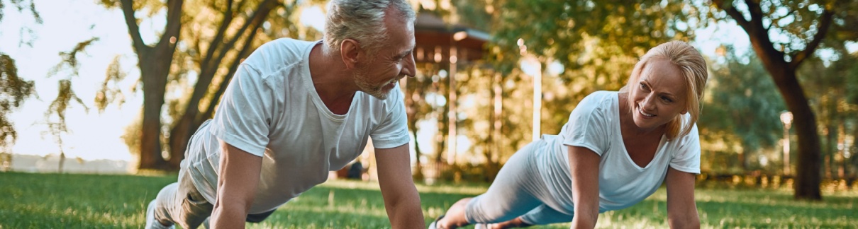 A couple doing yoga in a park.