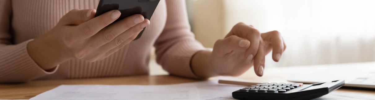 A woman using a phone and calculator.
