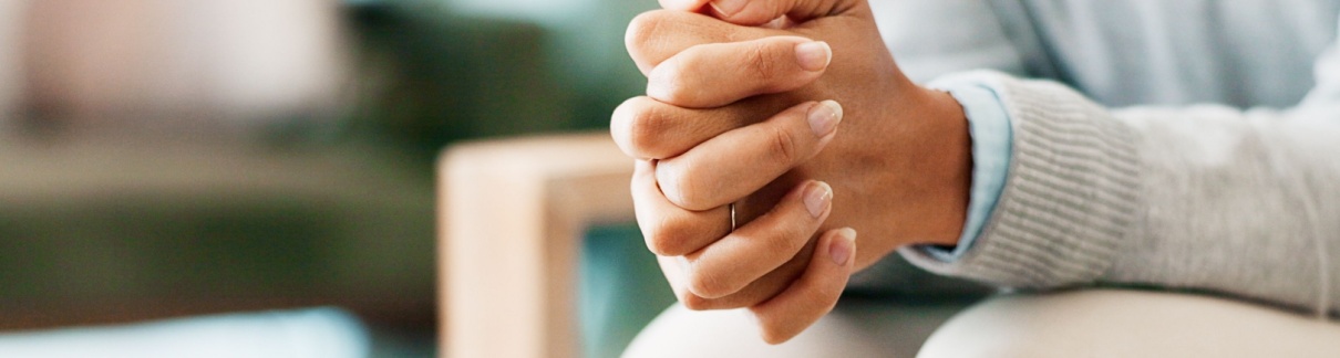 A woman sitting with her hands clasped.