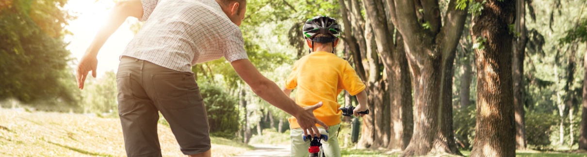 A father teaching a child to ride a bike.