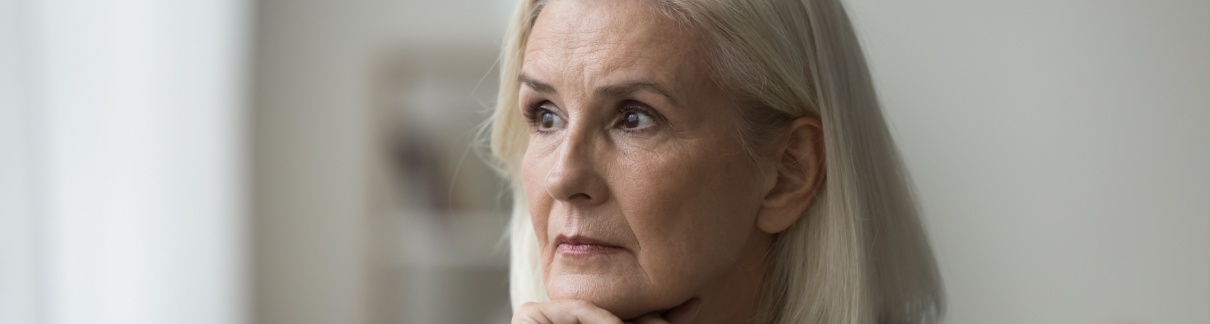 An older woman looks pensively off to one side.