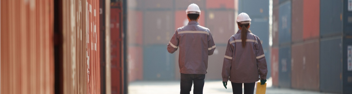 Two workers walking between shopping containers.