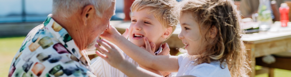 A grandfather playing with his grandchildren outdoors.
