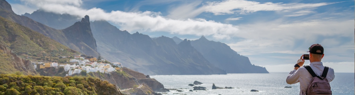 A male traveller taking a photo of a scenic coast.