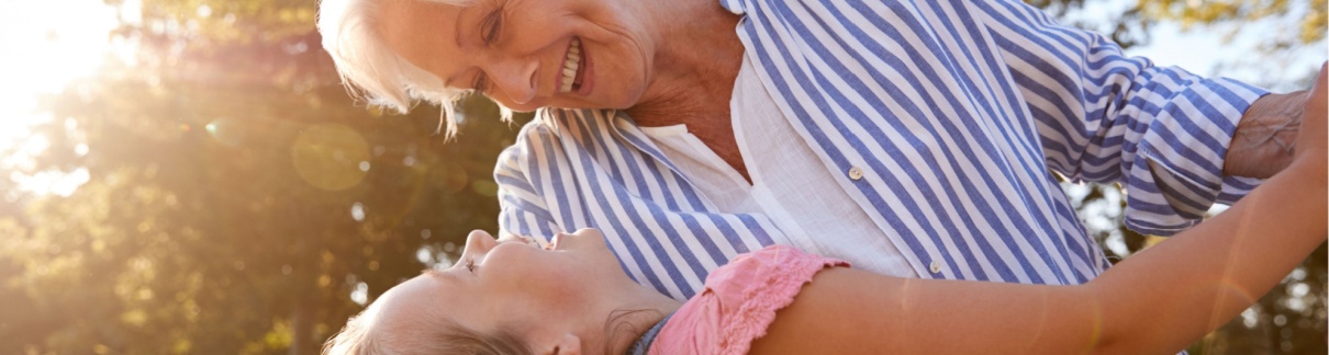 A grandmother playing with her granddaughter outside.