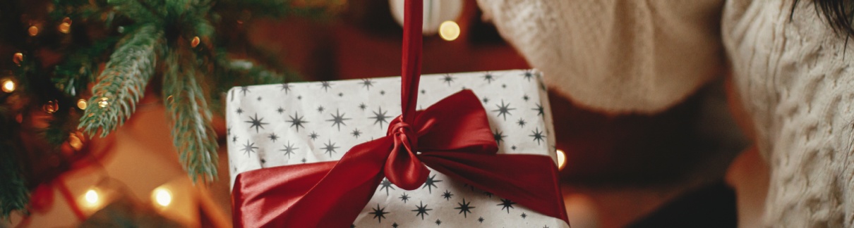 A woman untying a ribbon on a Christmas present.