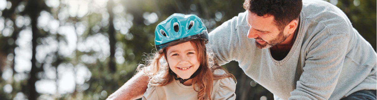 A father teaching his daughter to ride a bike.