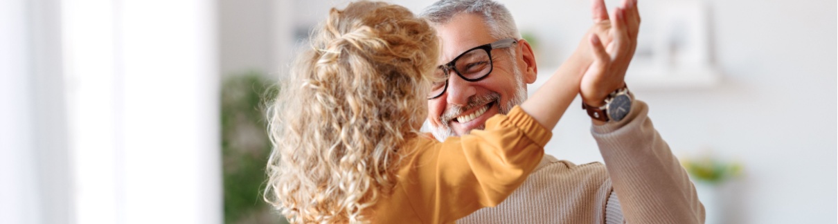 A grandfather playing with his granddaughter at home.