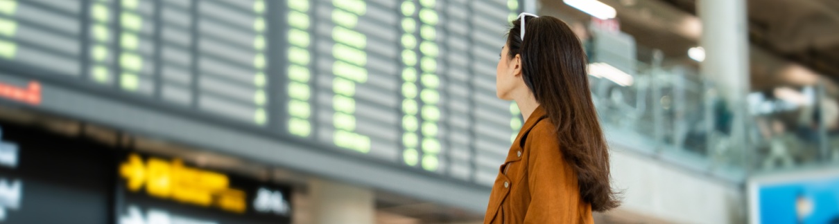 A woman looking at a departure board in an airport.