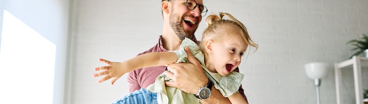 A father playing with his young daughter.