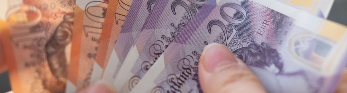 A person holding UK bank notes.