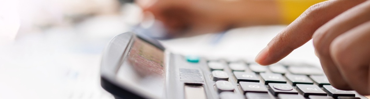 A person using a calculator while reviewing paperwork.