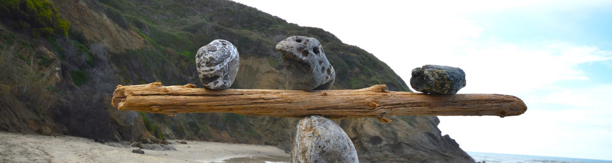 Rocks balancing on log on top of another rock